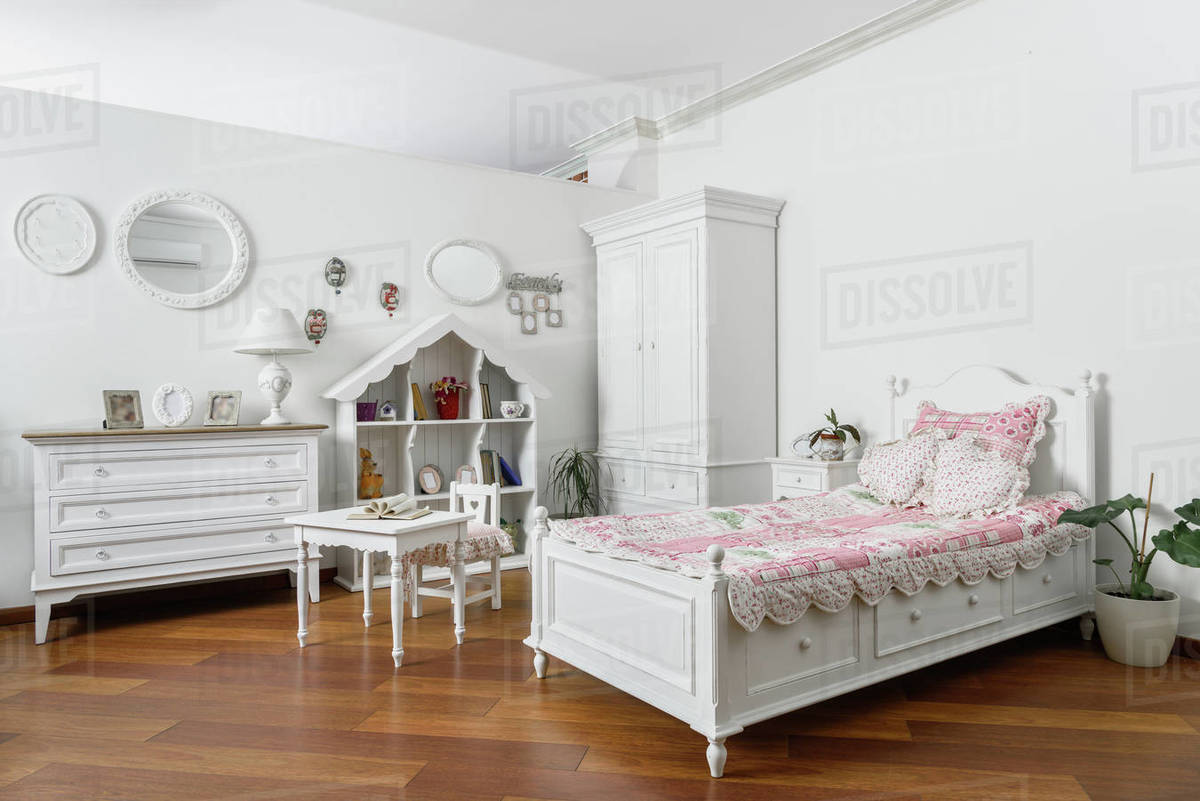 Interior of modern light bedroom with narrow bed and white furniture