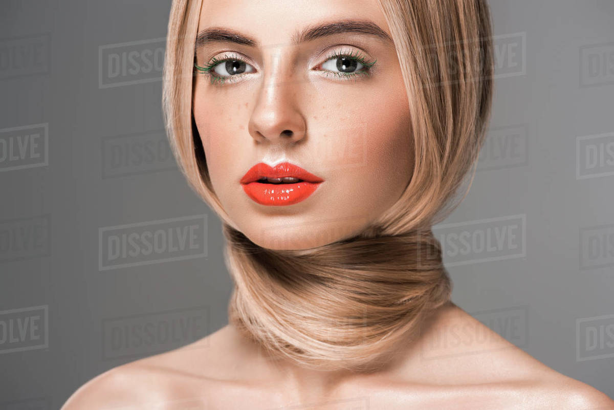 attractive naked girl with long hair wrapped around neck looking at camera isolated on grey