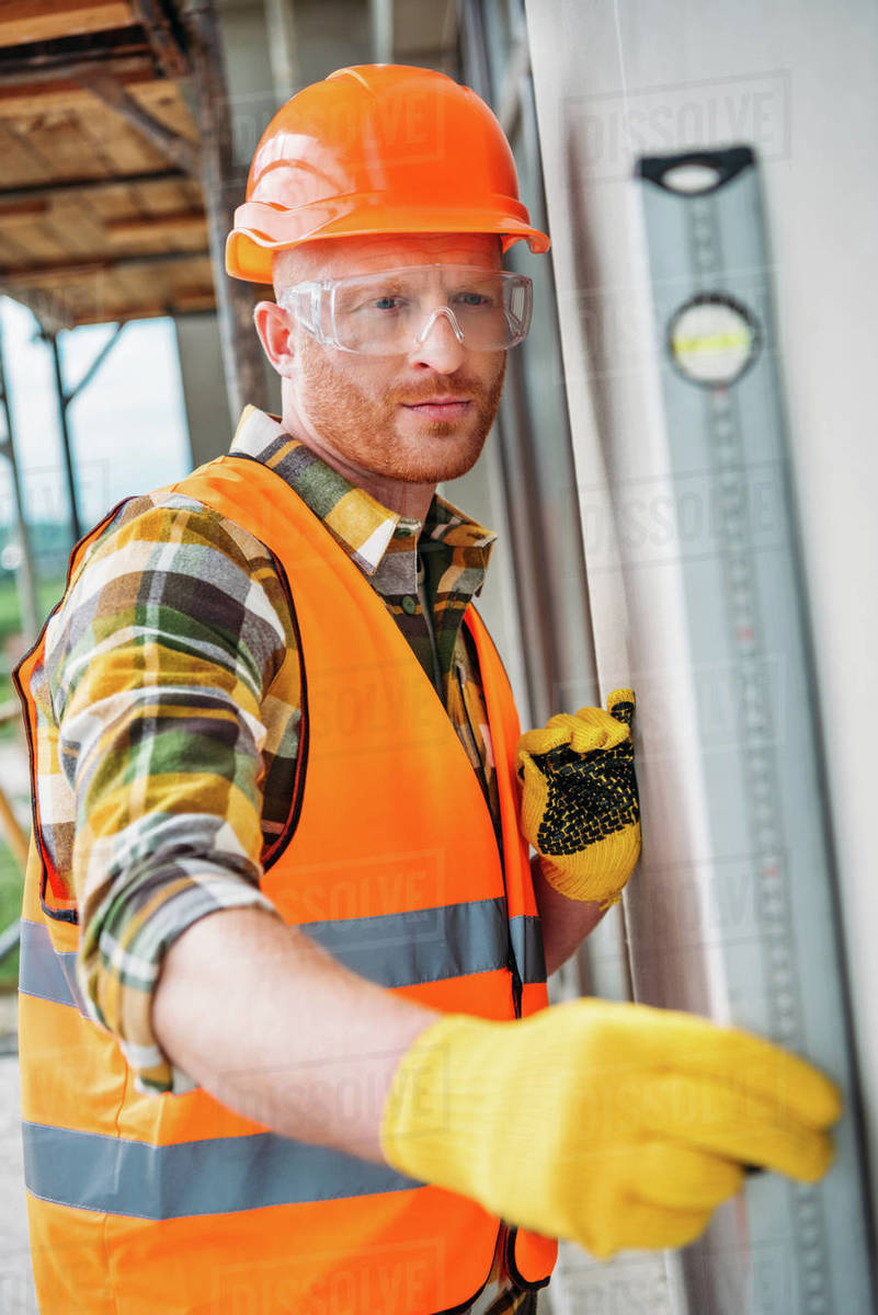Concentrated builder using bubble level at construction site Stock Photo Dissolve