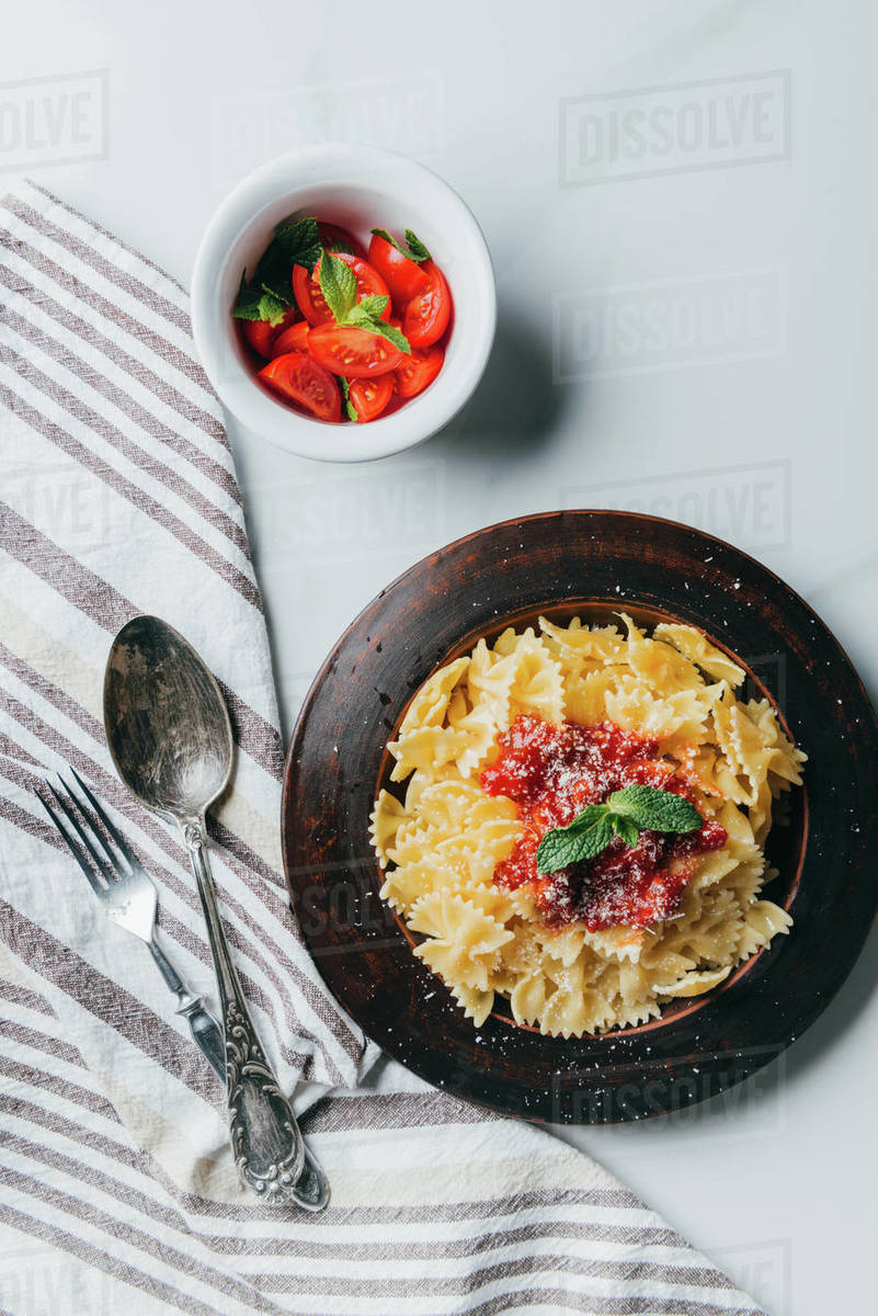 elevated view of plate with pasta, kitchen towel, fork, spoon and bowl