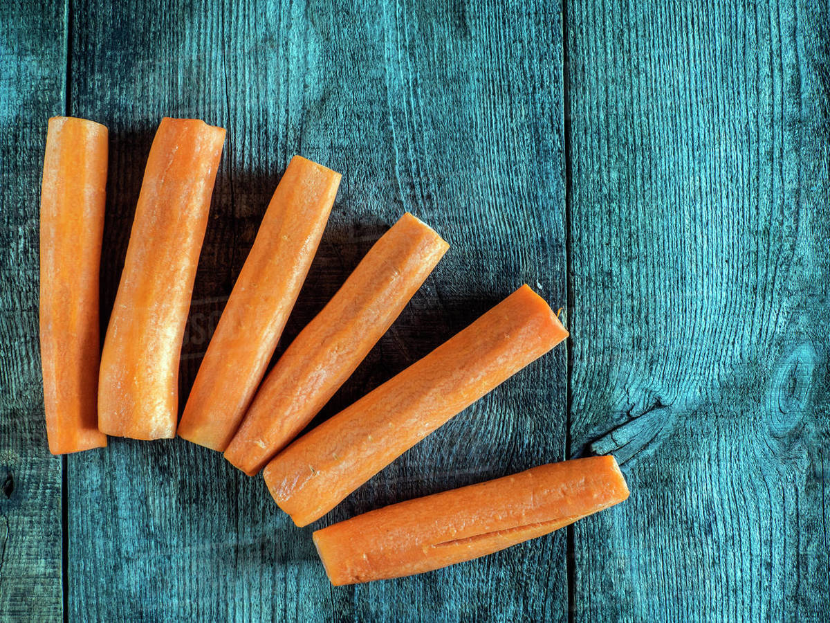 Overhead view of carrot batons on a wooden table Stock Photo Dissolve