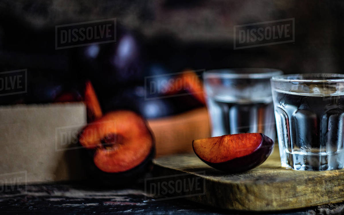 Two glasses of plum vodka on a chopping board with fresh plums Stock Photo Dissolve