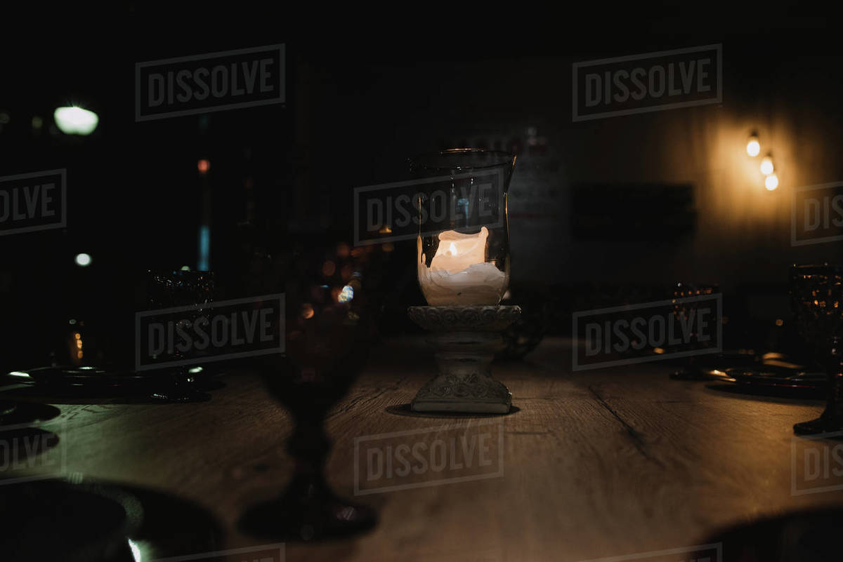 Small Candle Burning In Elegant Cup On Banquet Table In Dark Room In small-candle-burning-in-elegant-cup-on-banquet-table-in-dark-room-in