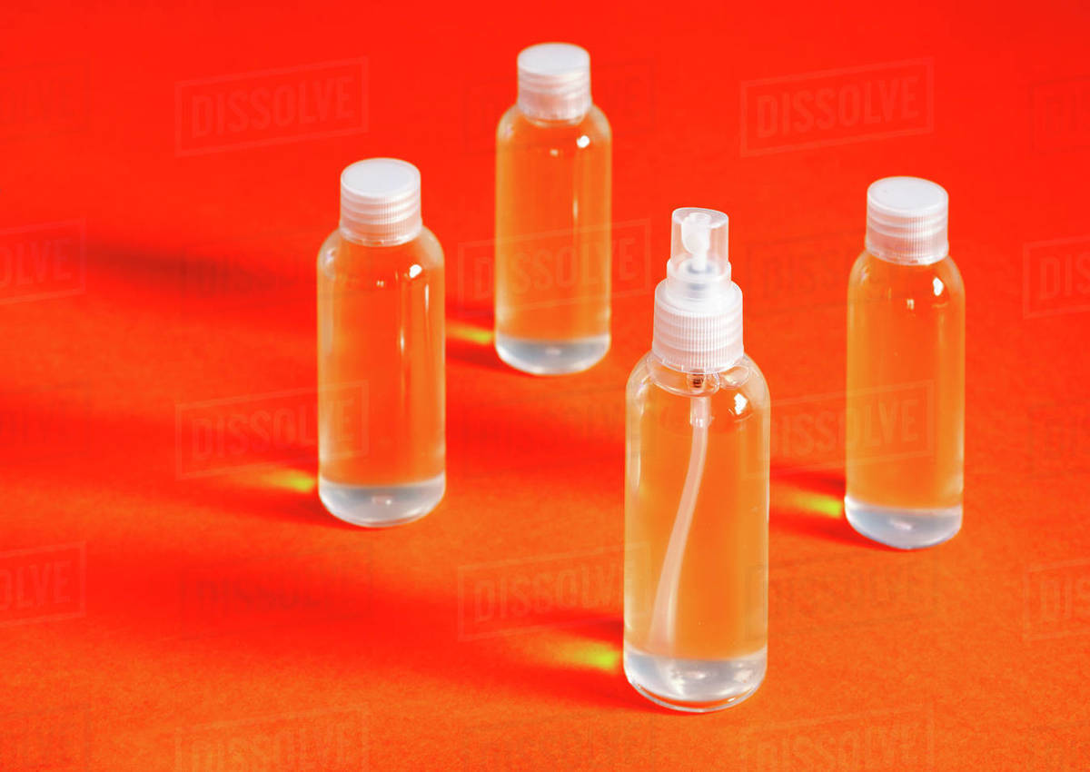 Sterile spray bottles on orange background. Stock Photo Dissolve