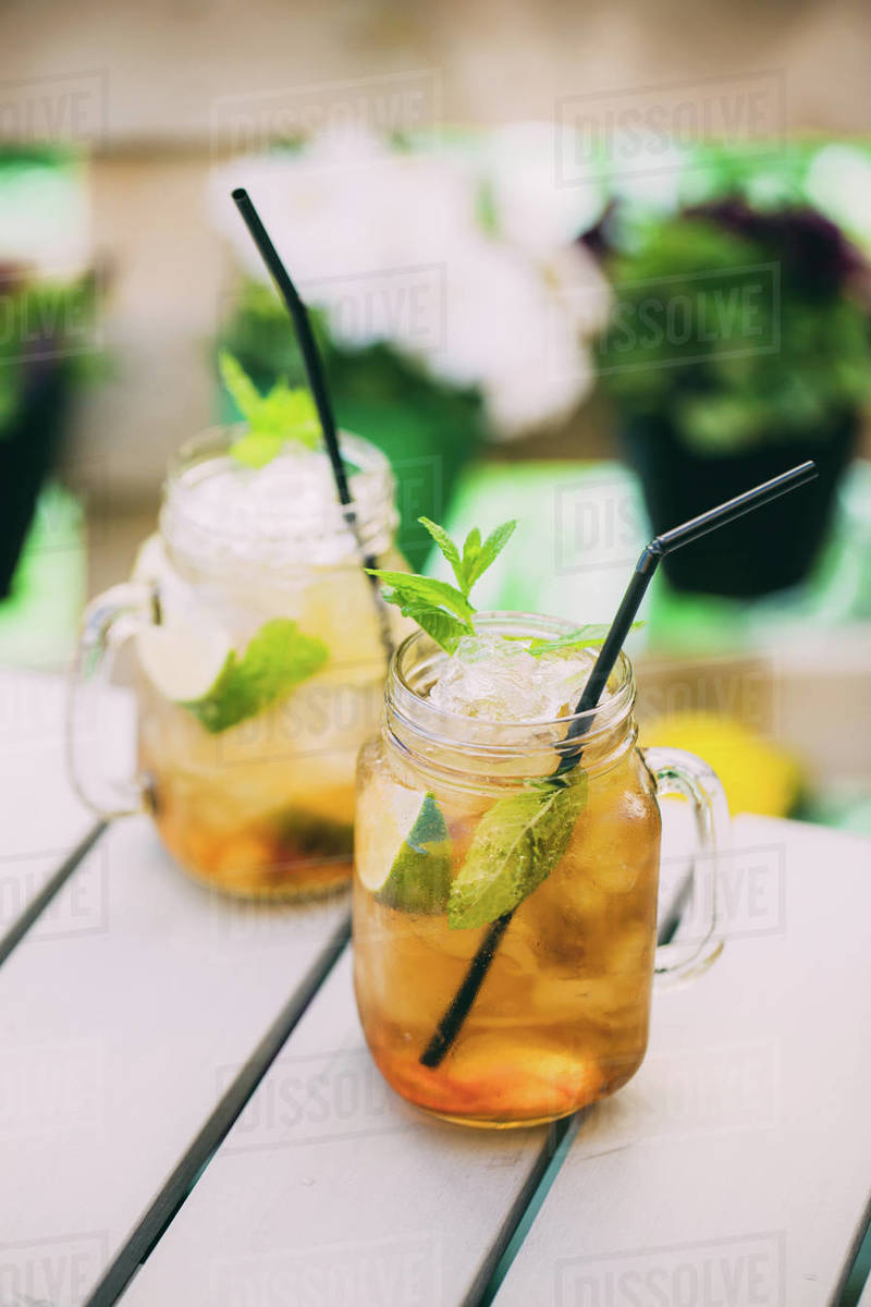 Mojitos cocktail prepared with lime, mint, rum, soda and ice in mason