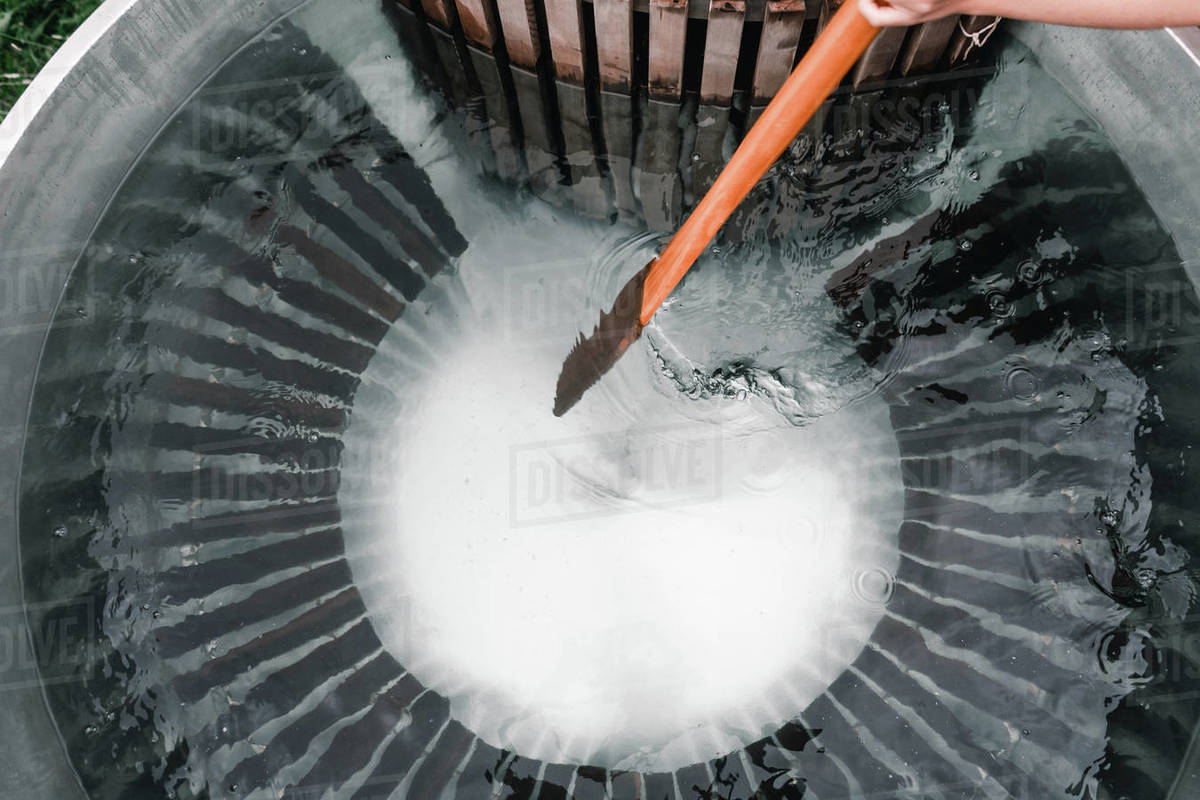 Anonymous man bathing in private woodfired hot tub holding a wooden
