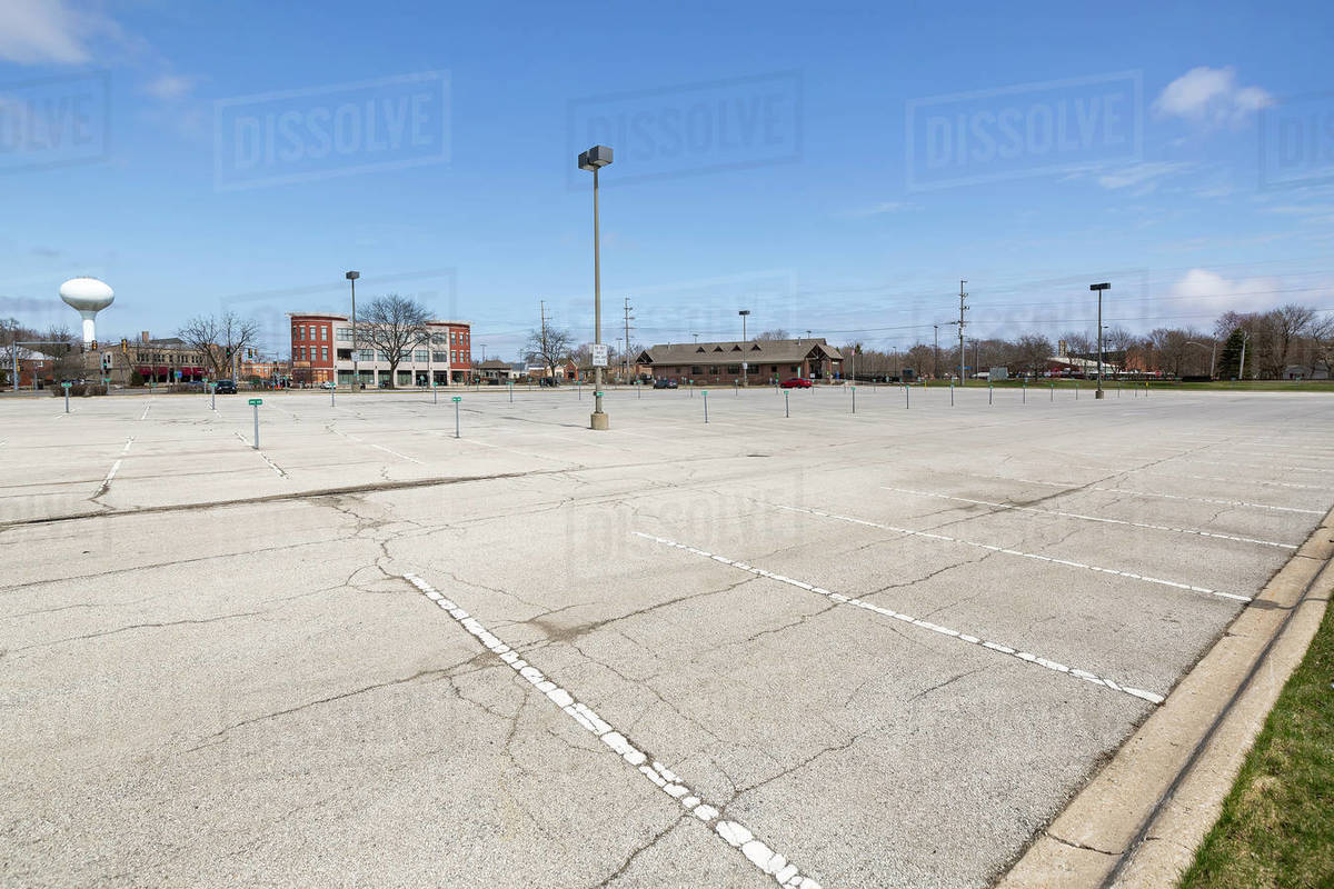 A suburban train station commuter parking lot is virtually empty during