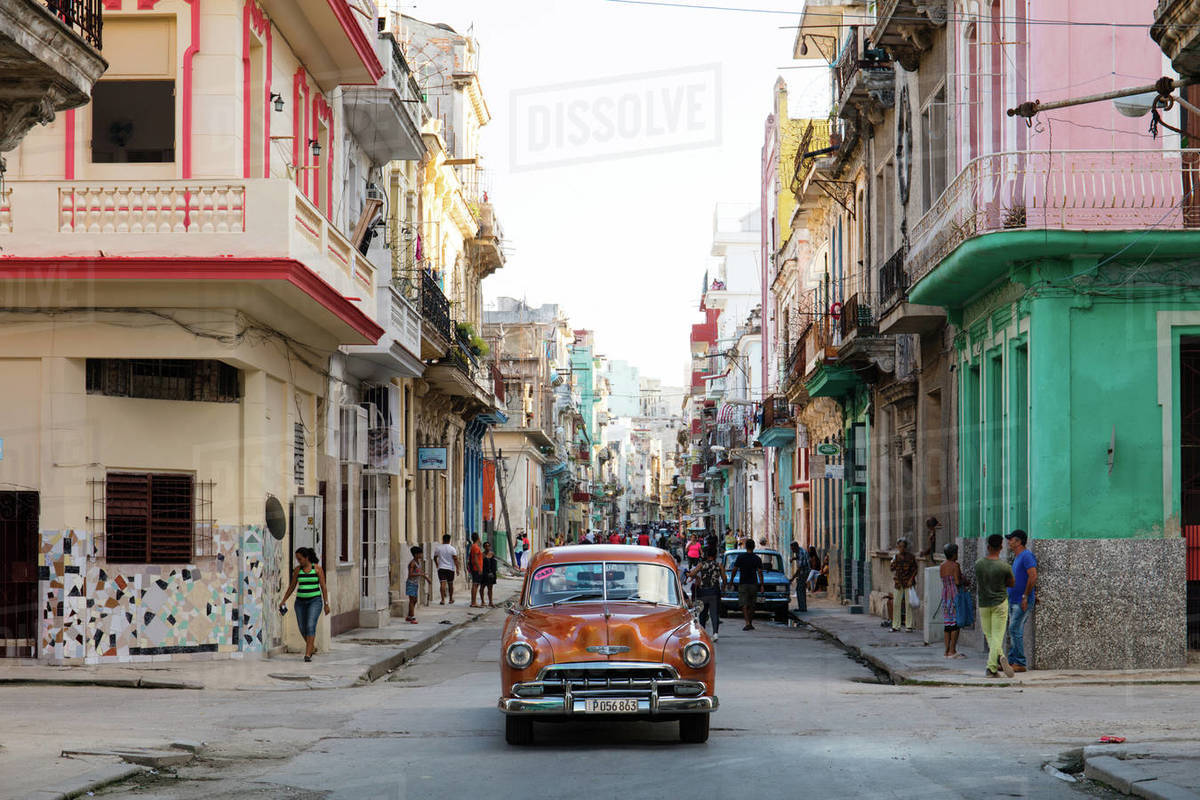 Red vintage car drives along old colourful street in Havana, Cuba, West Indies, Caribbean, Central America Royalty-free stock photo