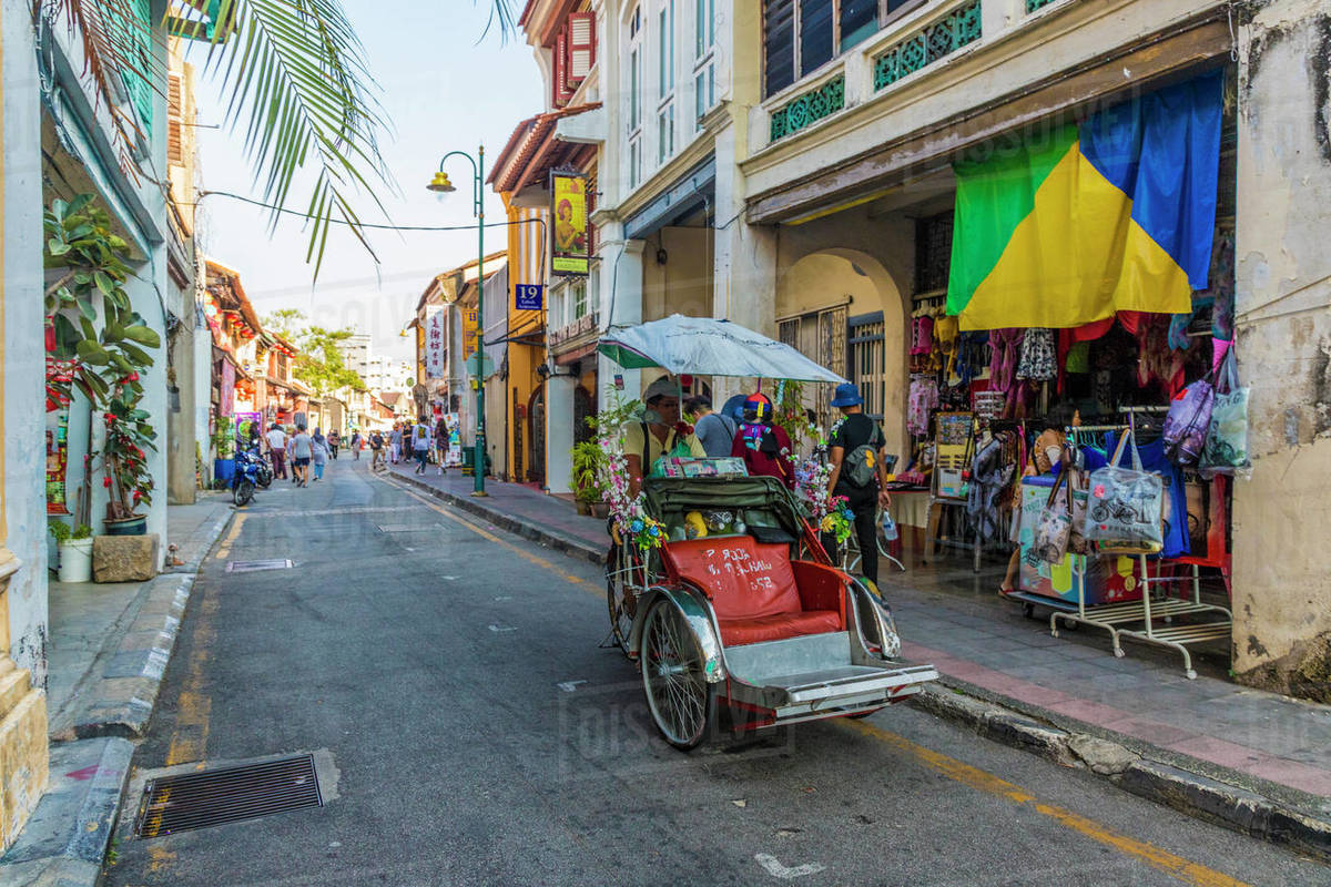 A local rickshaw (tuk tuk) driver in a colourful street scene in George Town, Penang Island, Malaysia, Southeast Asia, Asia Rights-managed stock photo