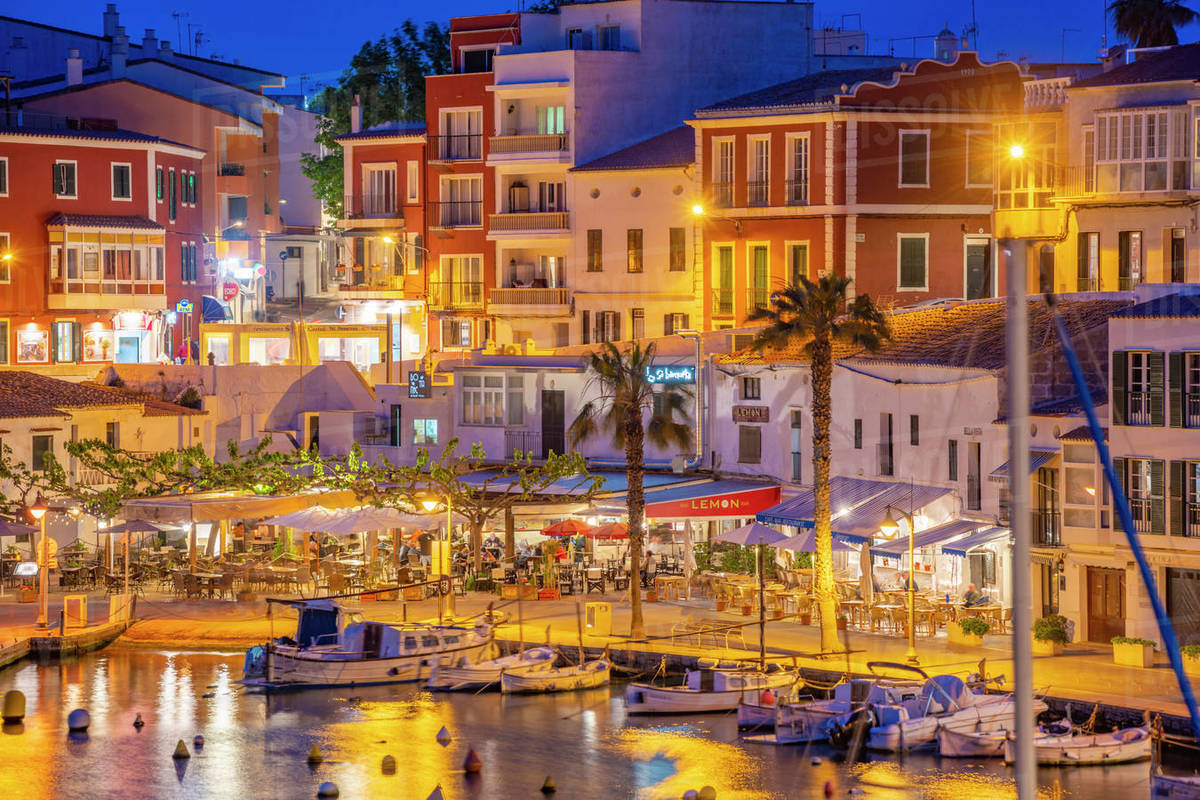 View of cafes, restaurants and boats in harbour at dusk, Cales Fonts ...
