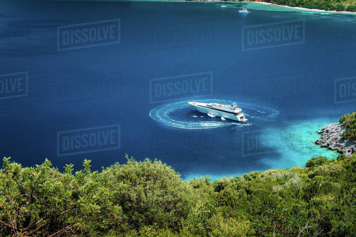 Luxury white yacht sail boat anchoring in a tranquil bay in deep blue