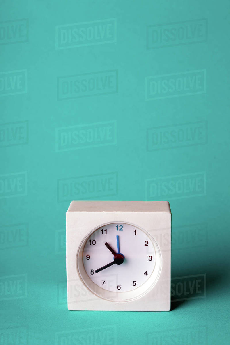 Small square white clock on a blue background Stock Photo Dissolve