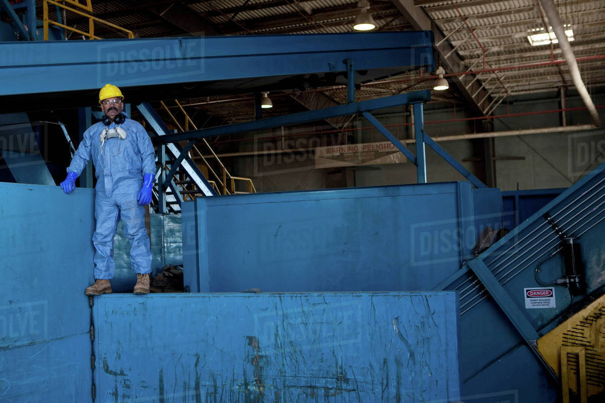 Portrait of male worker in hard hat standing on blue heavy machinery at