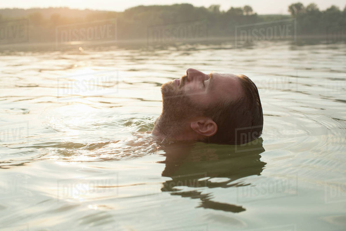 Man relaxing, floating in river Stock Photo Dissolve