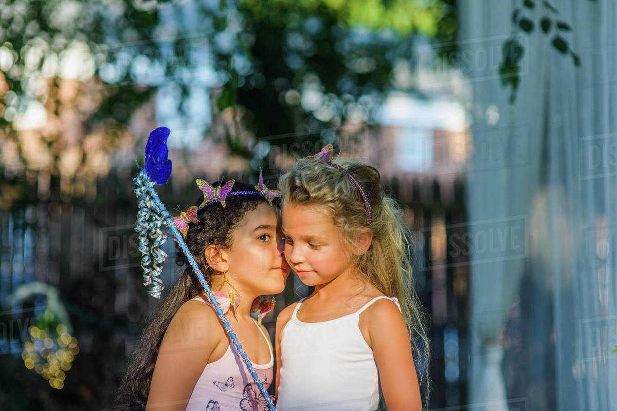 Two young girls dressed as fairies, girl whispering in friend's ear Royalty-free stock photo