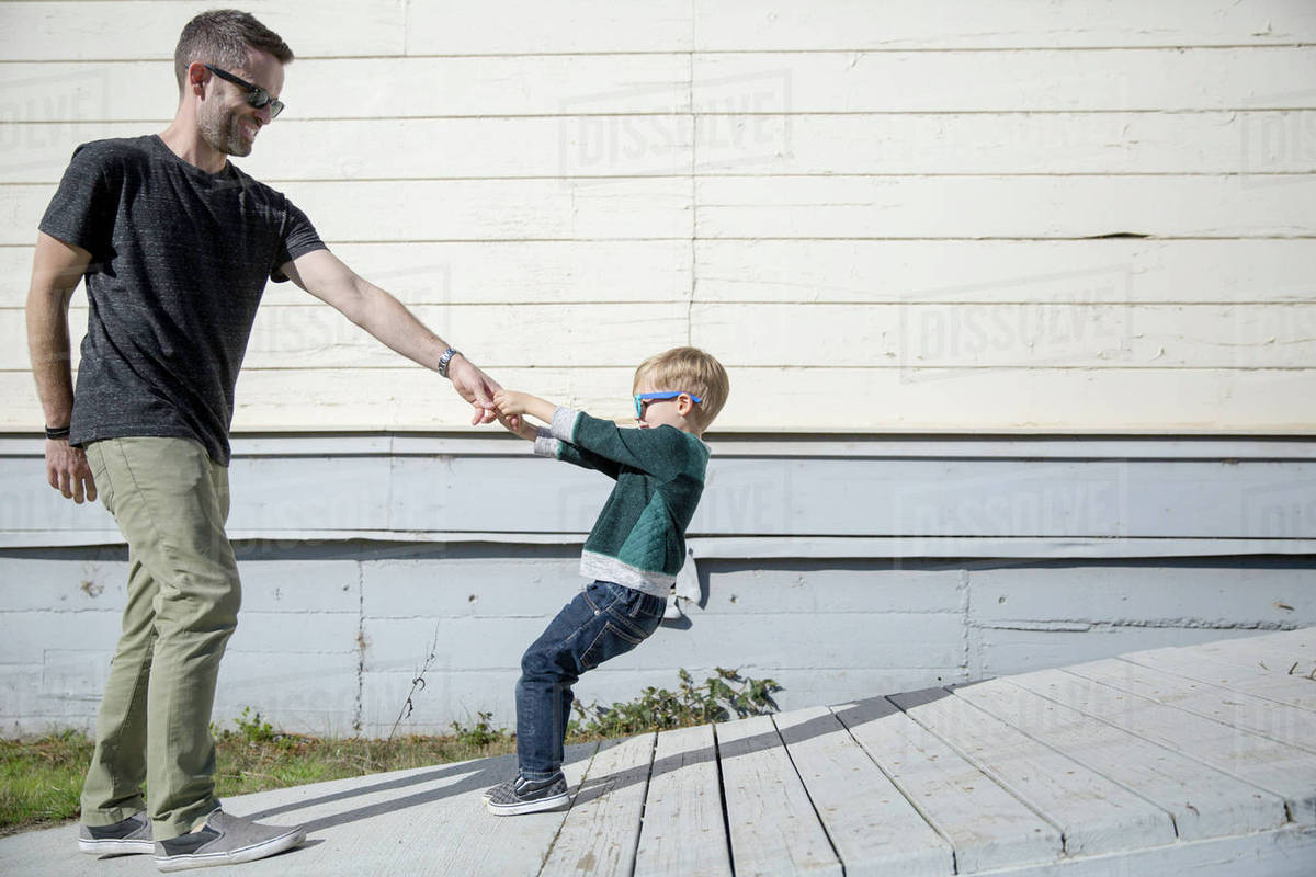 Boy pulling father up wooden ramp Stock Photo Dissolve