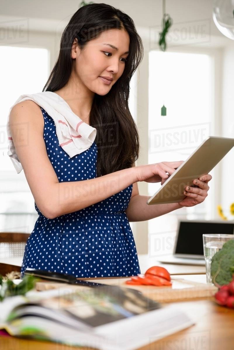 Woman with tea towel over shoulder using digital tablet Stock Photo