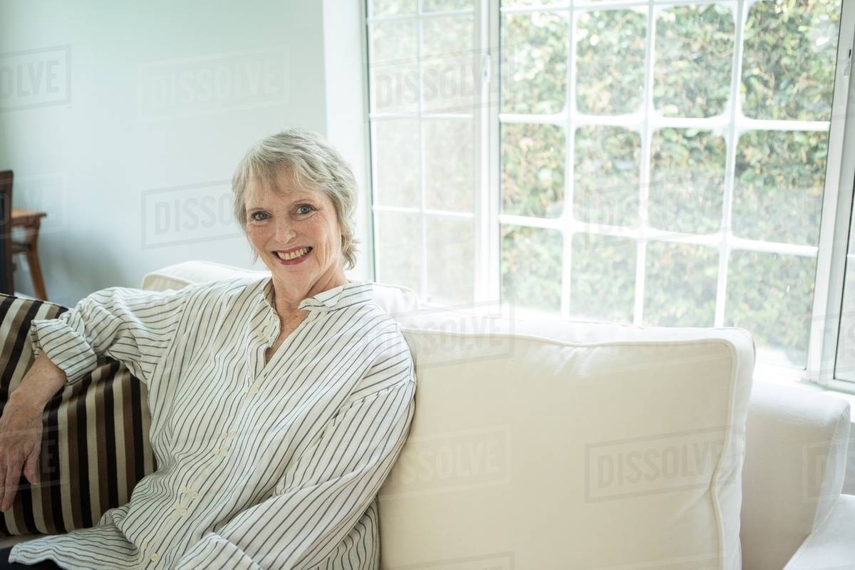 Senior woman on sofa, portrait Stock Photo Dissolve