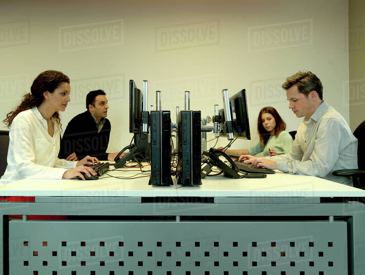 Business people using computers at desk - Stock Photo - Dissolve