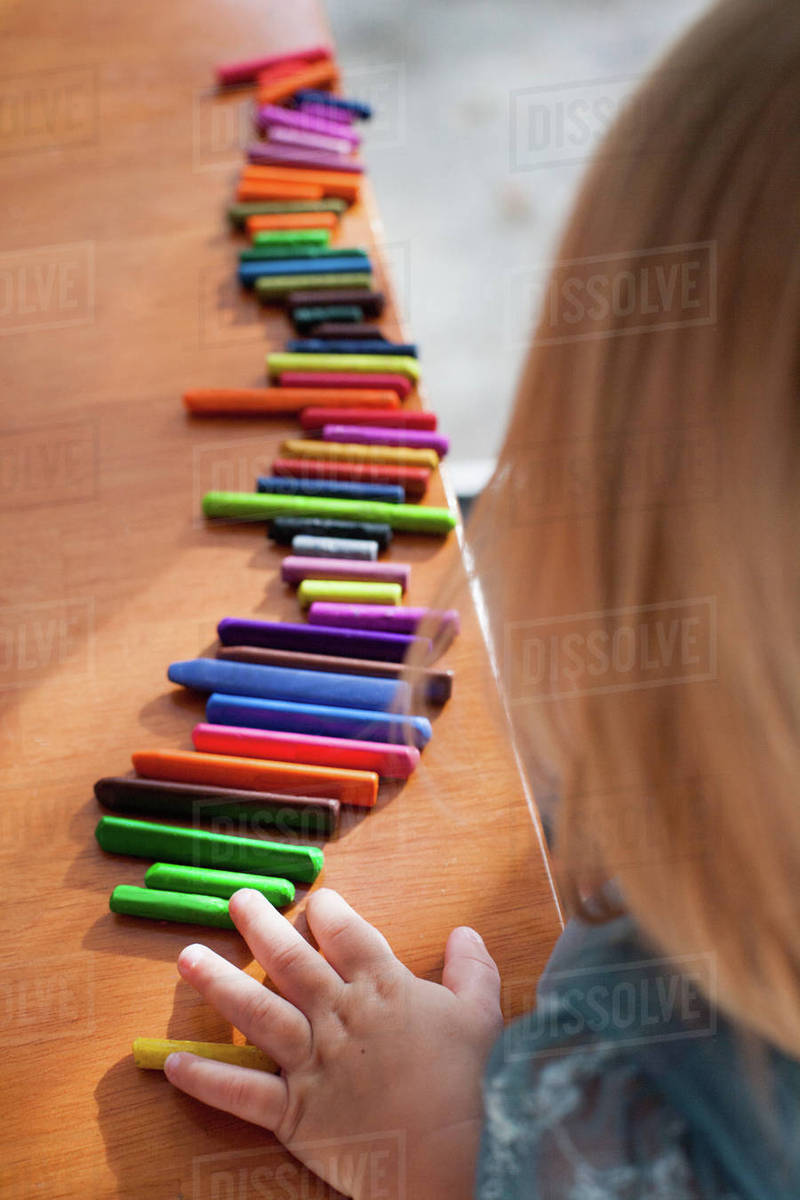 Girl lining up crayons in a row Stock Photo Dissolve