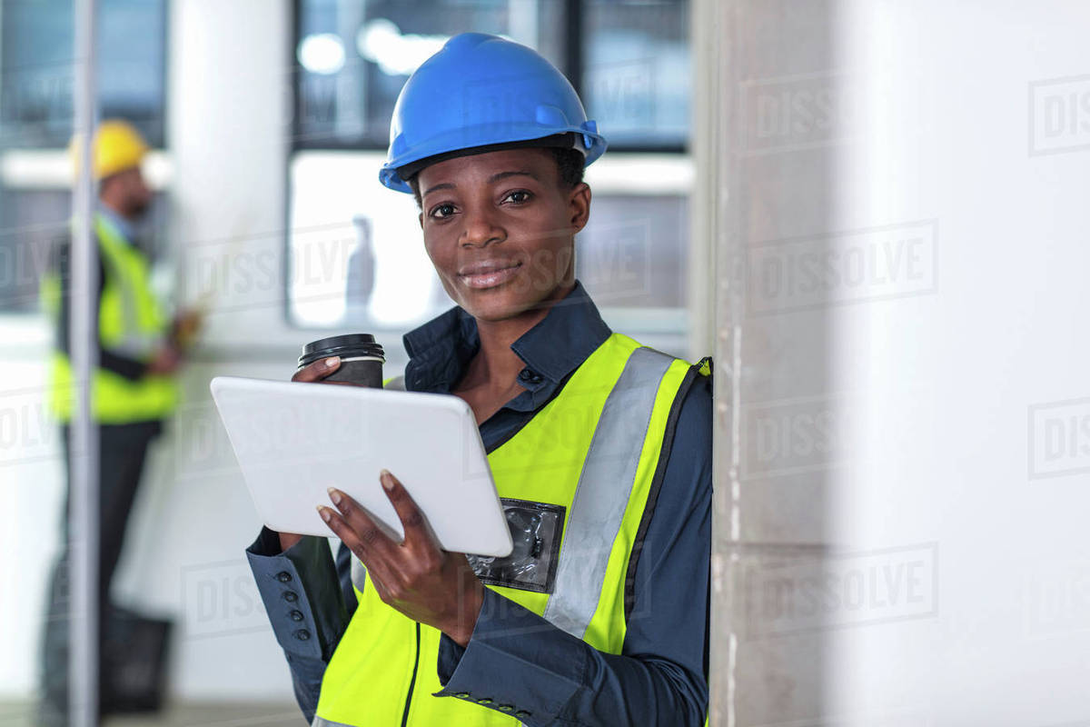 woman with hard hat and hi viz jacket using digital tablet stock