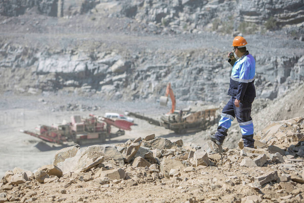 Quarry worker in quarry, talking into walkie talkie Stock Photo