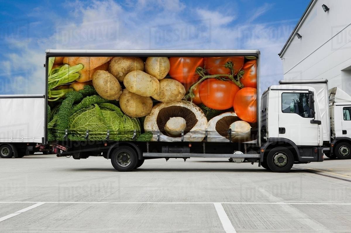 Truck with vegetables parked outside distribution warehouse - Stock