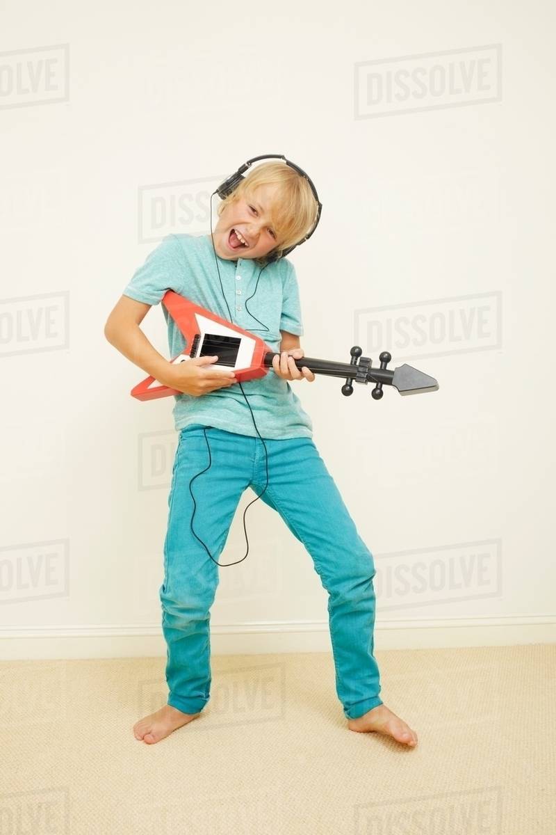 Boy wearing headphones playing guitar Stock Photo Dissolve
