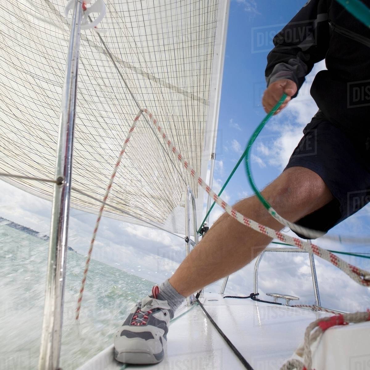 Man on yacht, pulling ropes Stock Photo Dissolve