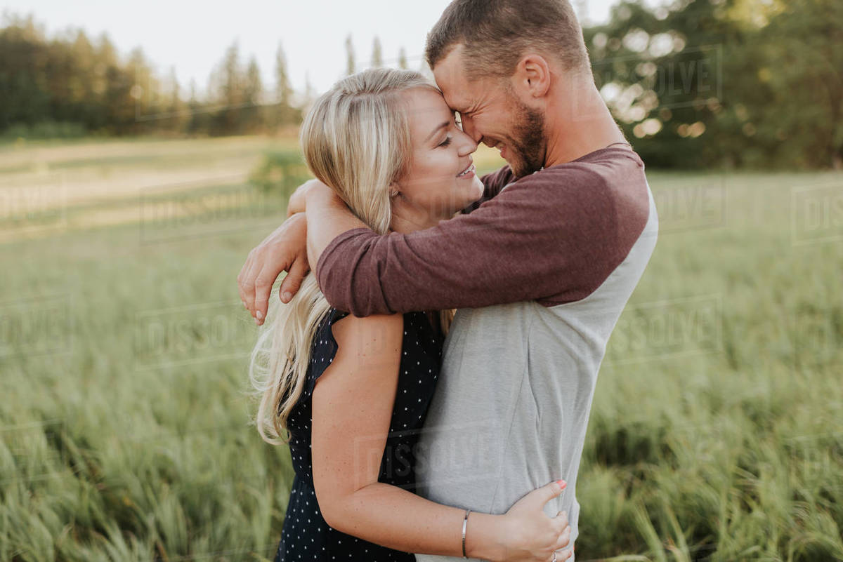 Romantic man and girlfriend hugging in field of long grass