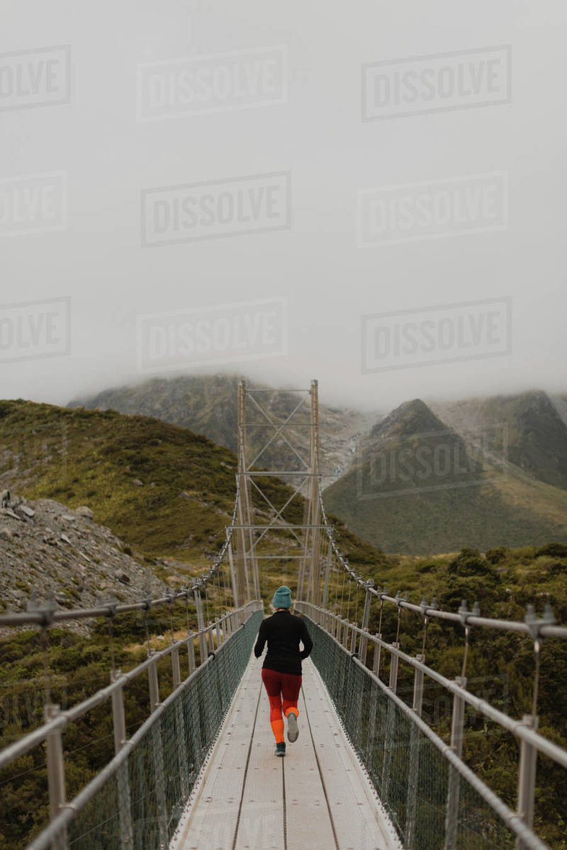 Hiker crossing suspension bridge, Wanaka, Taranaki, New Zealand Stock
