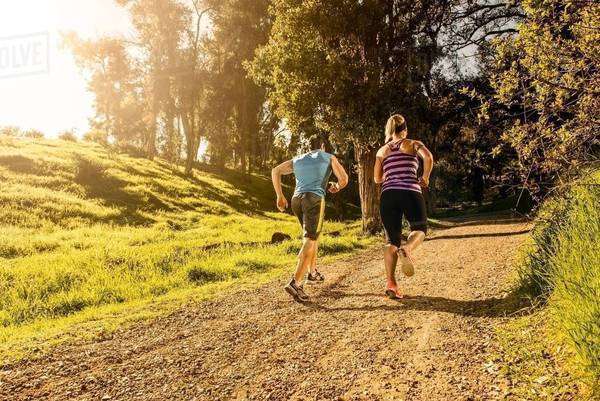 Two people jogging on forest path - Stock Photo - Dissolve