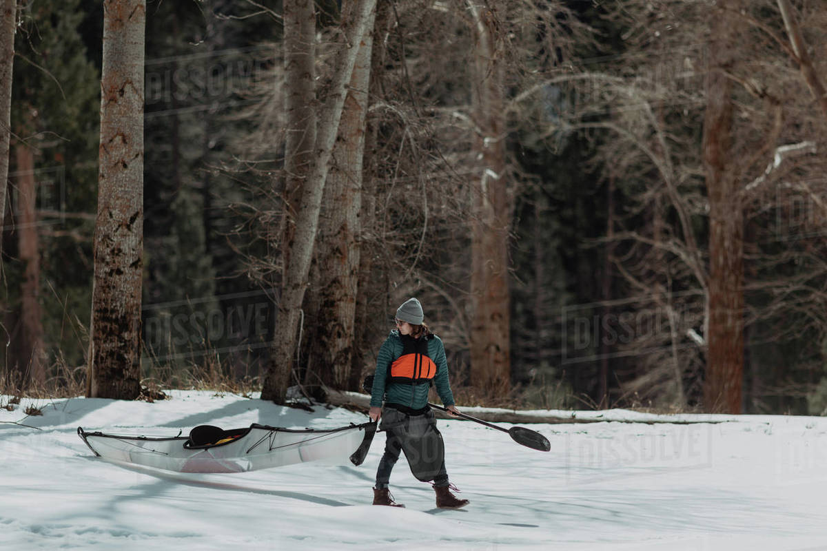 Man dragging kayak across snow, Yosemite Village, California, United