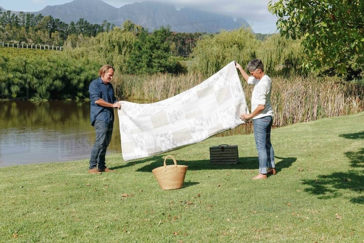 Couple folding picnic blanket by pond, Cape Town, South Africa Stock