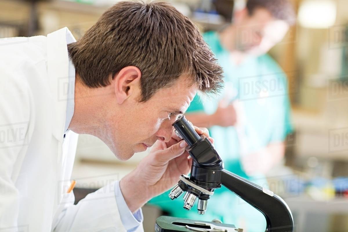 Doctor using microscope Stock Photo Dissolve