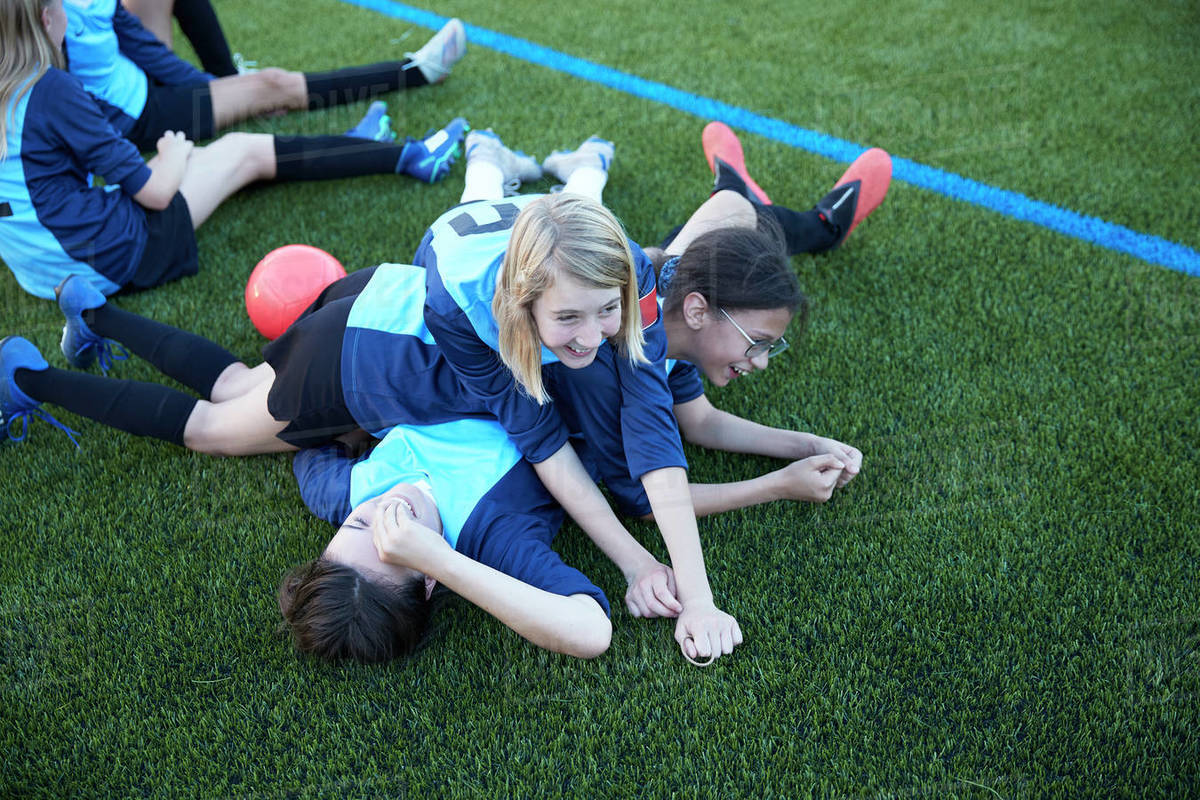 Playful female soccer players lying in field Stock Photo Dissolve