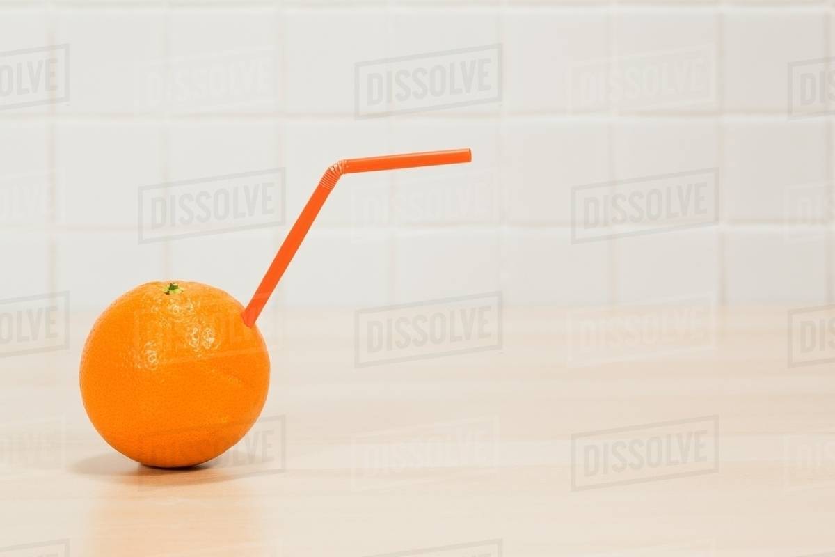 Orange with drinking straw sticking out Stock Photo Dissolve