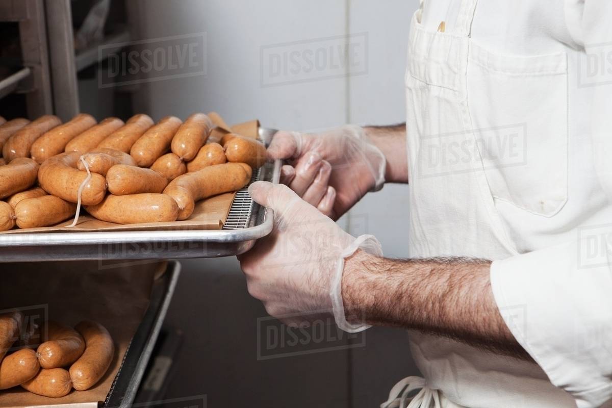 Butcher with tray of sausages Stock Photo Dissolve