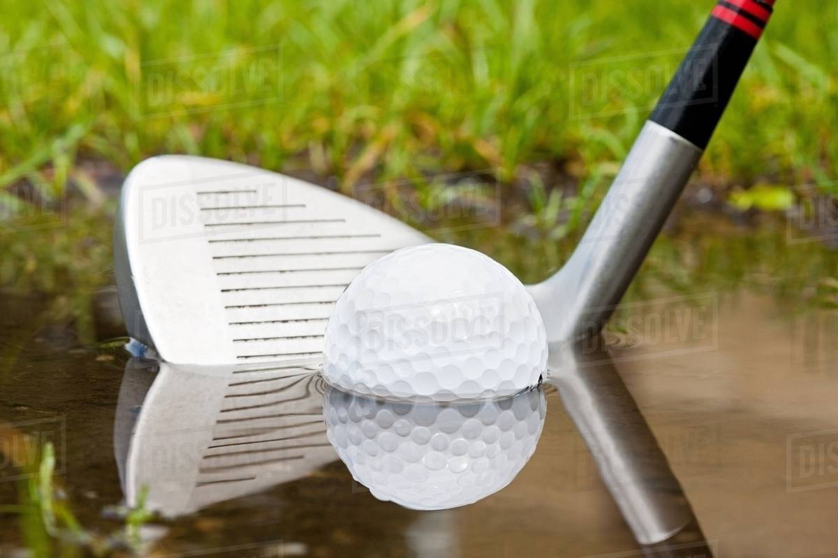 Golf club hitting golf ball out of water Stock Photo Dissolve