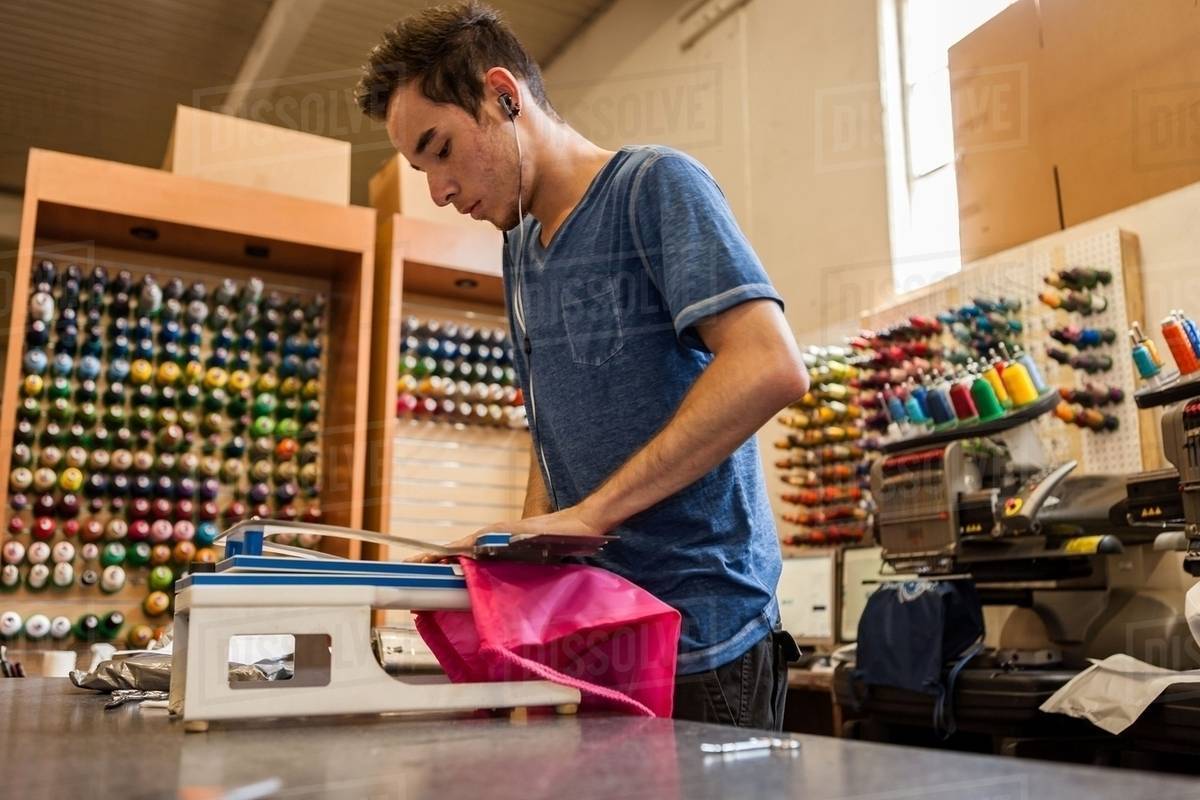 Worker using embroidery machine in tshirt printing Stock