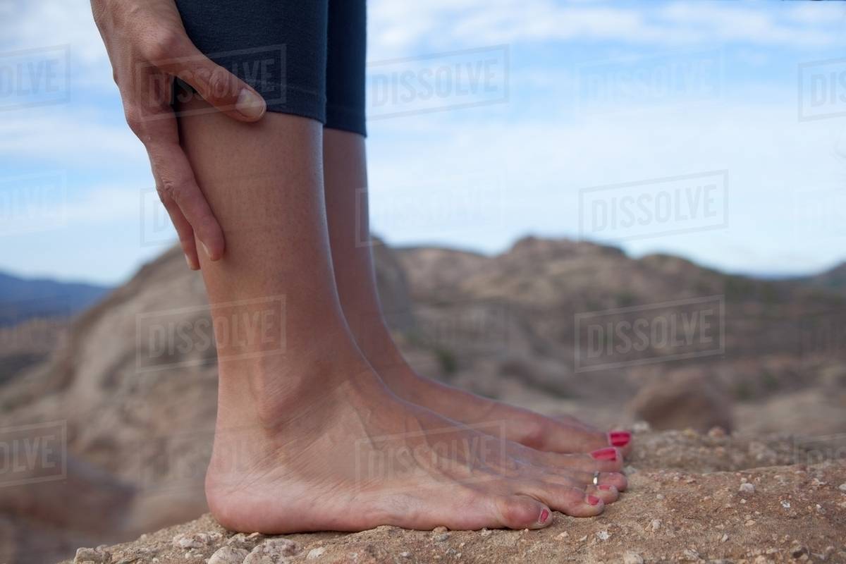 Cropped image of woman's bare feet standing on rocks Stock Photo