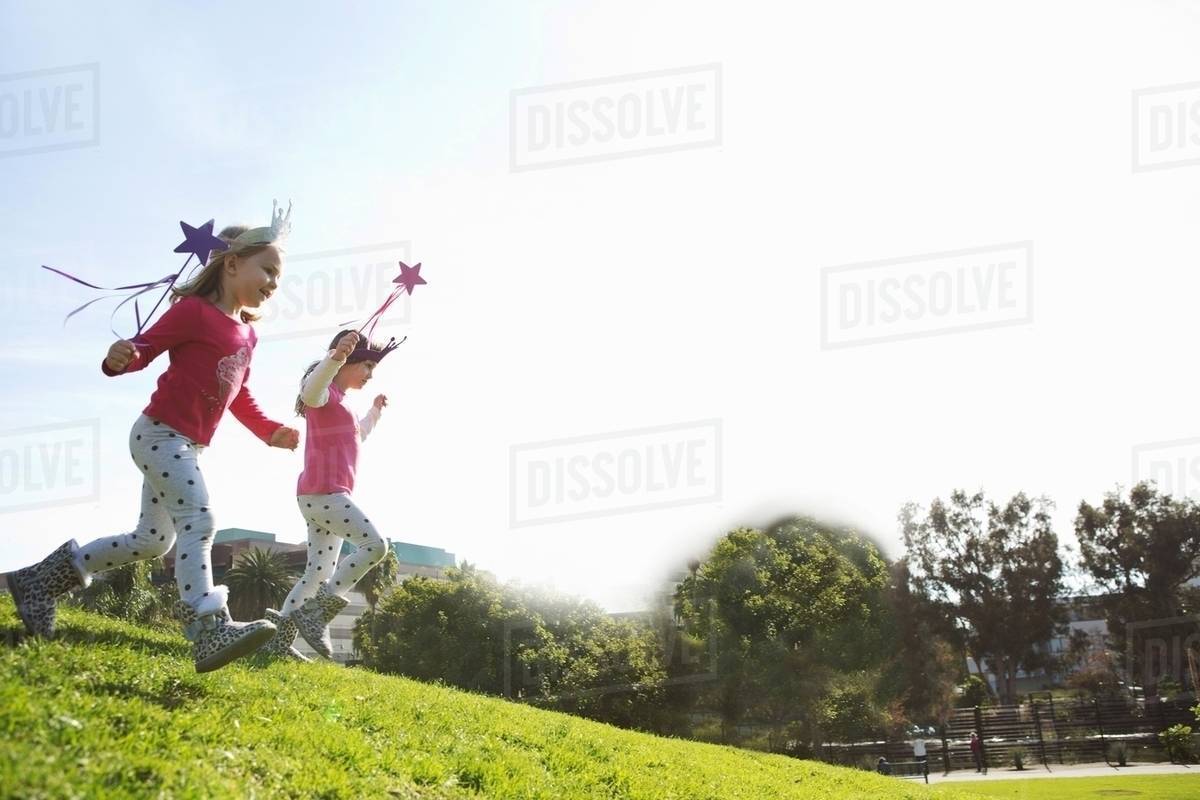 Two young sisters dressed up as fairies running down hill Royalty-free stock photo