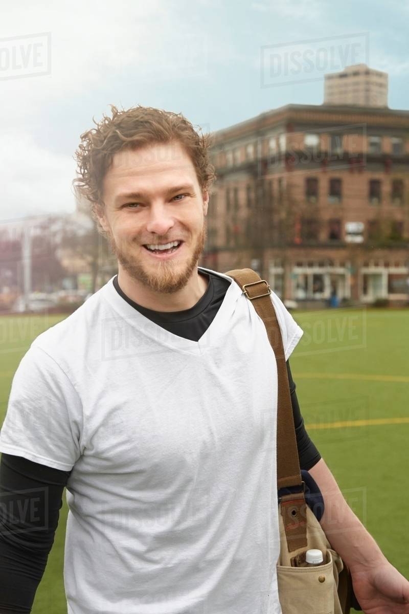 Portrait of mid adult male soccer player carrying gym bag on soccer pitch Stock Photo Dissolve