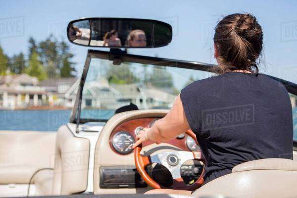 Rear view of young woman driving motor boat, Lake Oswego, Oregon, USA ...
