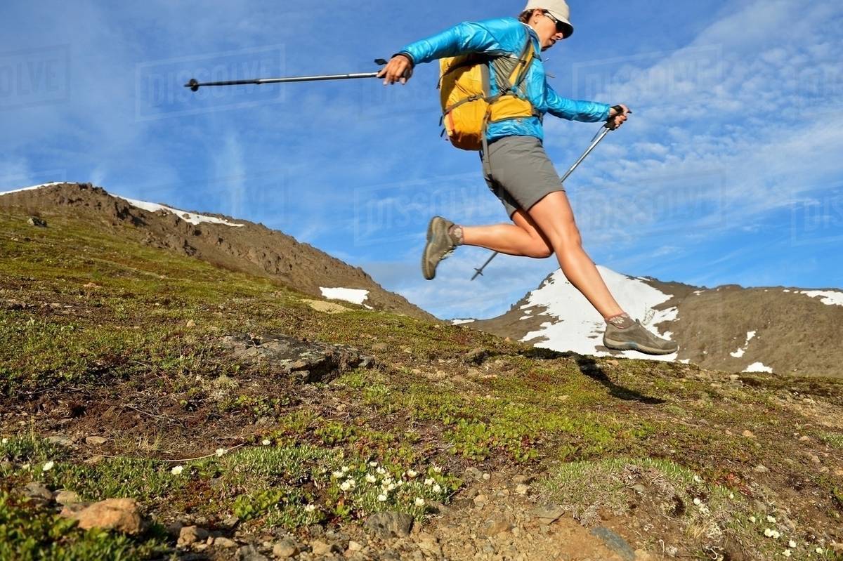 Female mountain climber jumping downhill, Chugach State Park, Anchorage, Alaska, USA Royalty-free stock photo