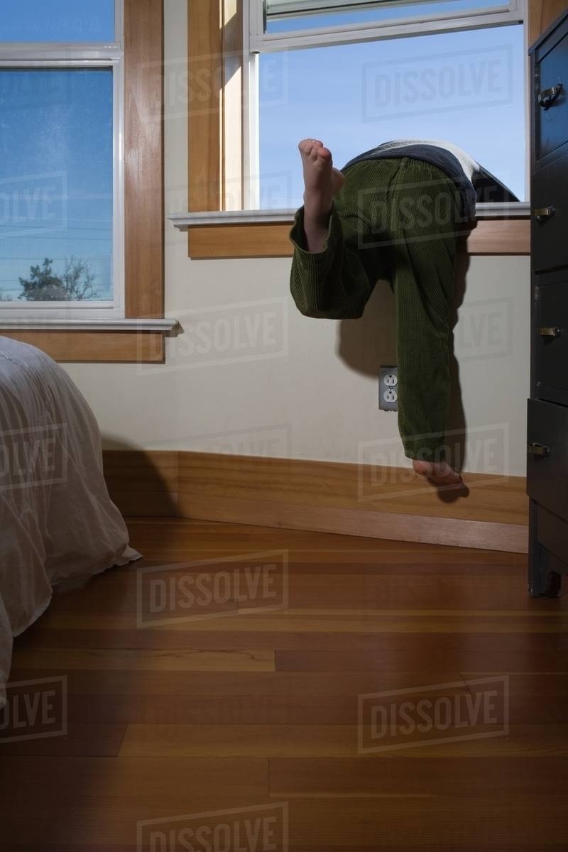 Boy climbing out of window Stock Photo Dissolve