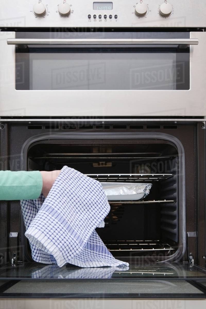 Person putting dish in oven Stock Photo Dissolve