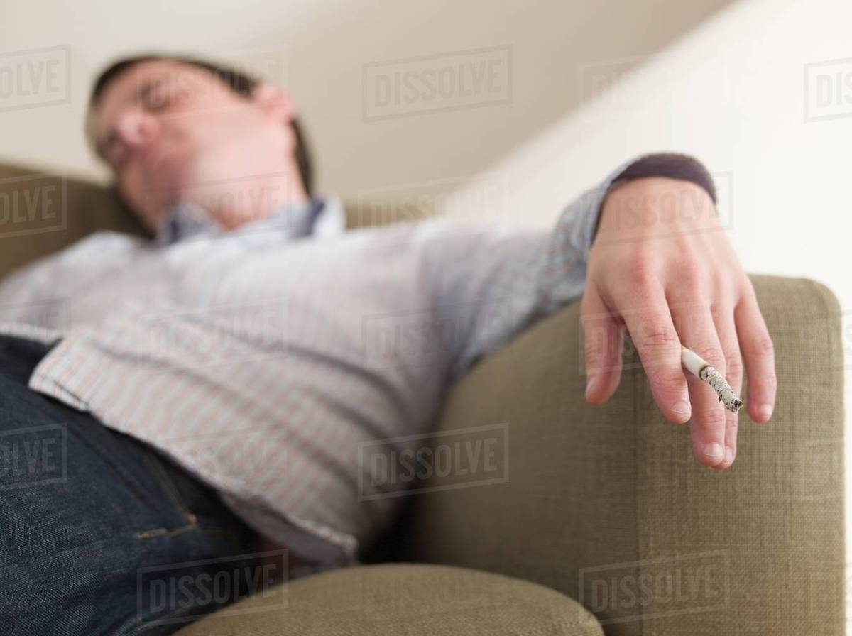sleeping cigarette A man asleep with a cigarette in his hand - Royalty-free Stock Photo