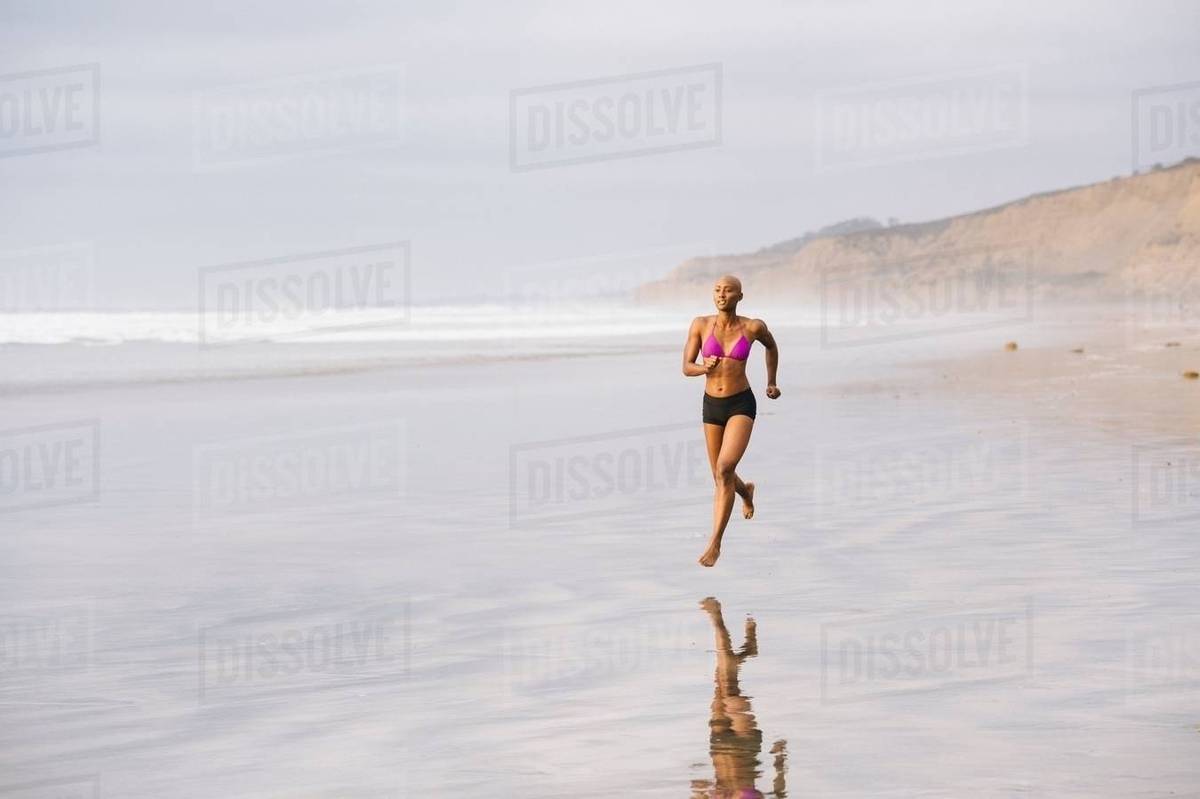 Woman in bikini jogging on beach Stock Photo Dissolve