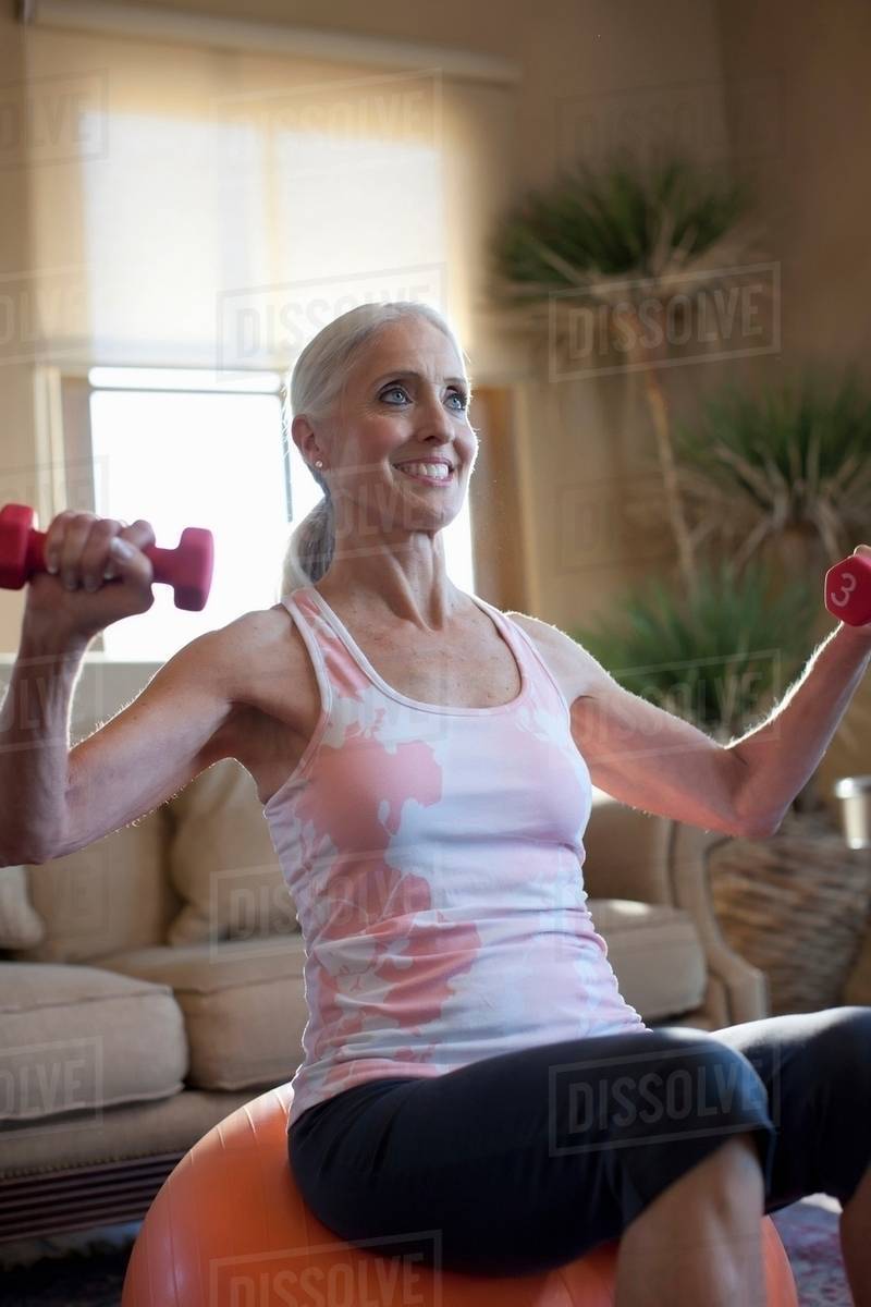 older-woman-lifting-weights-at-home-stock-photo-dissolve